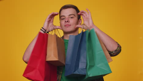 hombre turista feliz mostrando bolsas de compras, promocionando descuentos de vacaciones, asombrado por los bajos precios