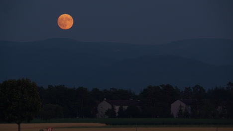 luna llena sobre las montañas y las casas