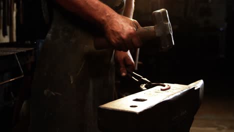 mid-section of blacksmith working on a horseshoe