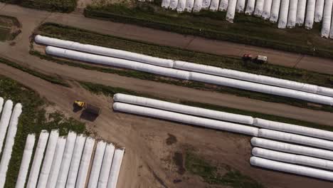 Aerial-top-down-of-Tractor-transporting-Harvest-of-Silo-Bags-on-Farmland-Field-during-sunny-day