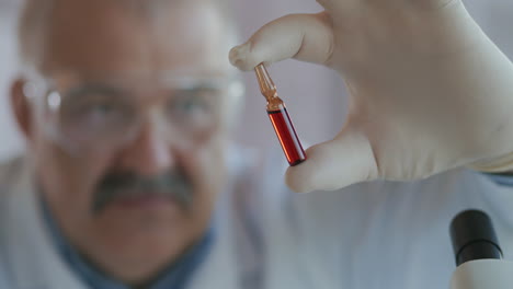 tratamiento de inmunización covid-19 coronavirus. retrato cercano de un médico de sexo masculino con gafas protectoras sosteniendo un tubo de ensayo con la inscripción vacuna covid-19 sars-cov-2 en su mano. imágenes de alta calidad 4k