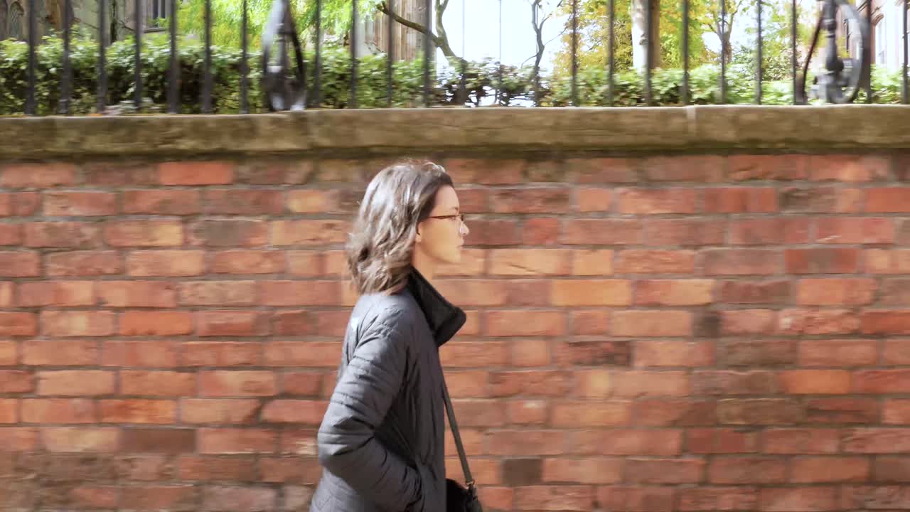 벽돌 벽을 배경으로 걷고 있는 젊은 여성의 클로즈업 프로필 사진