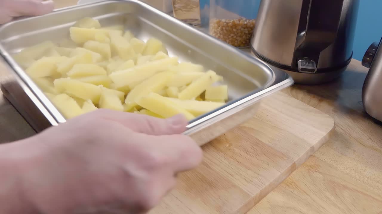 tiro deslizante en cámara lenta de sacudir papas sancochadas para papas fritas en una bandeja de metal para hornear
