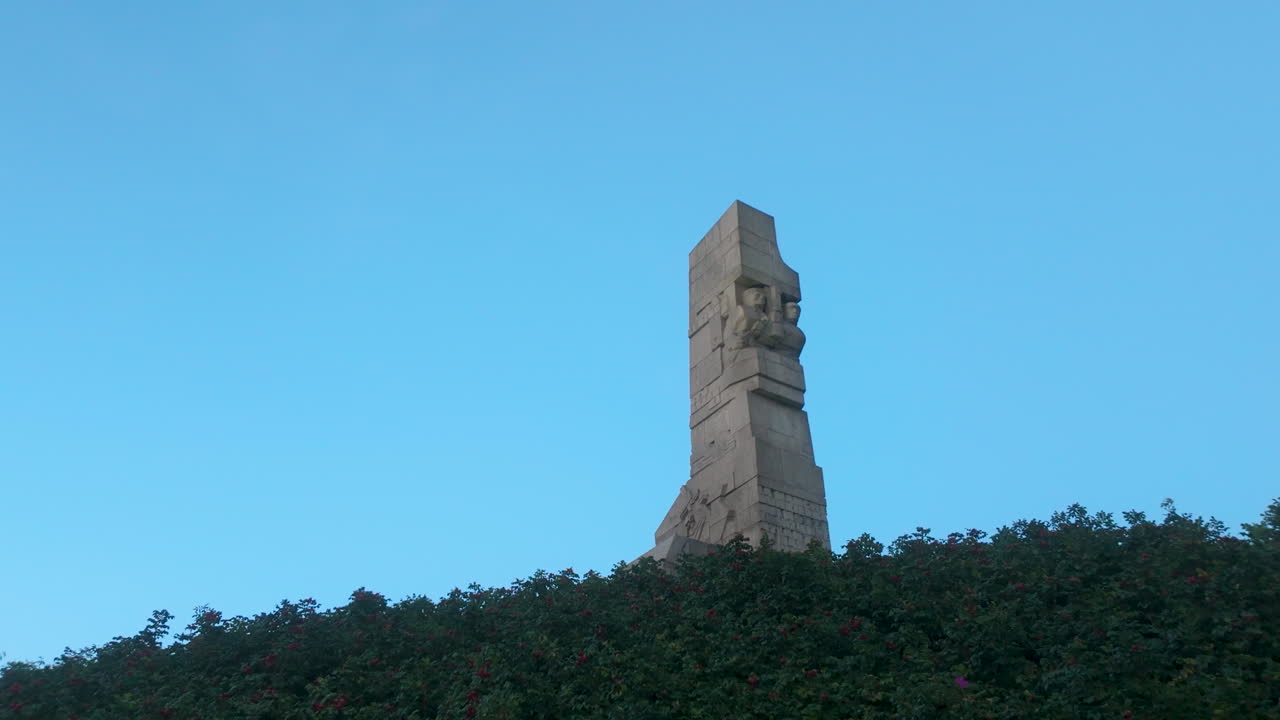 Stone monument on a hill surrounded by greenery under clear blue sky during sunset - Westerplatte, Poland