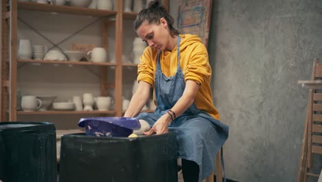 young serious woman making ceramic pottery on the wheel