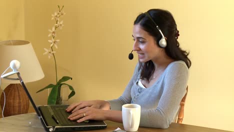 Mujer-Sonriente-Hablando-Por-Internet-Con-Auriculares-Puestos