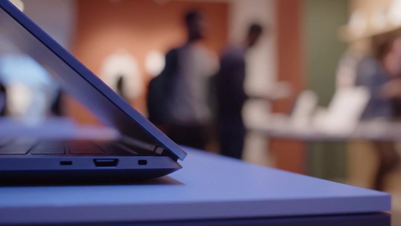 Un laptop moderno esposto in un elegante ambiente di vendita al dettaglio, che evidenzia il design tecnologico e l'atmosfera mentre gli acquirenti interagiscono in un'esperienza interattiva