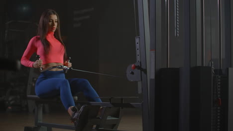 the ripped woman is training her shoulder blades on the training machine in gym. she is keeping her back straight while exercising.