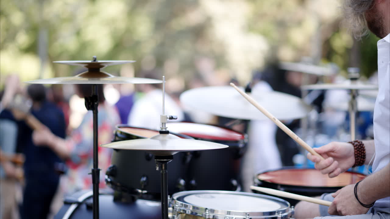 Close up of man playing the drums with a band outside