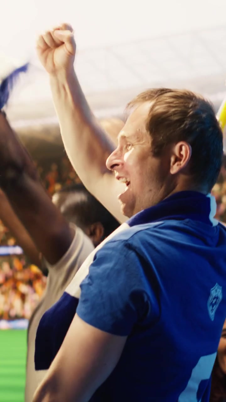 Video vertical: Vista trasera de aficionados de fútbol felices con camisetas azules levantando los puños para celebrar