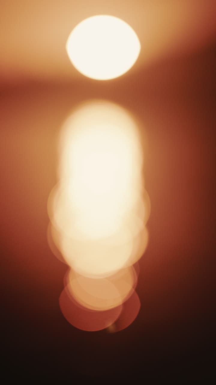 Scatto astratto e fuori fuoco del sole e del suo riflesso sul mare. Verticale