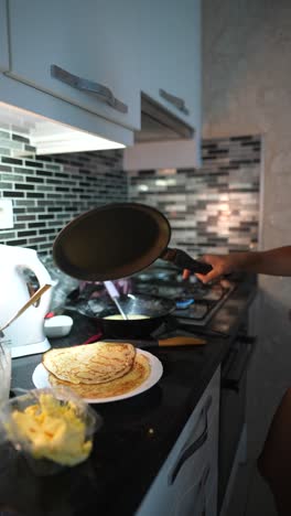 young woman cooking pancakes at home
