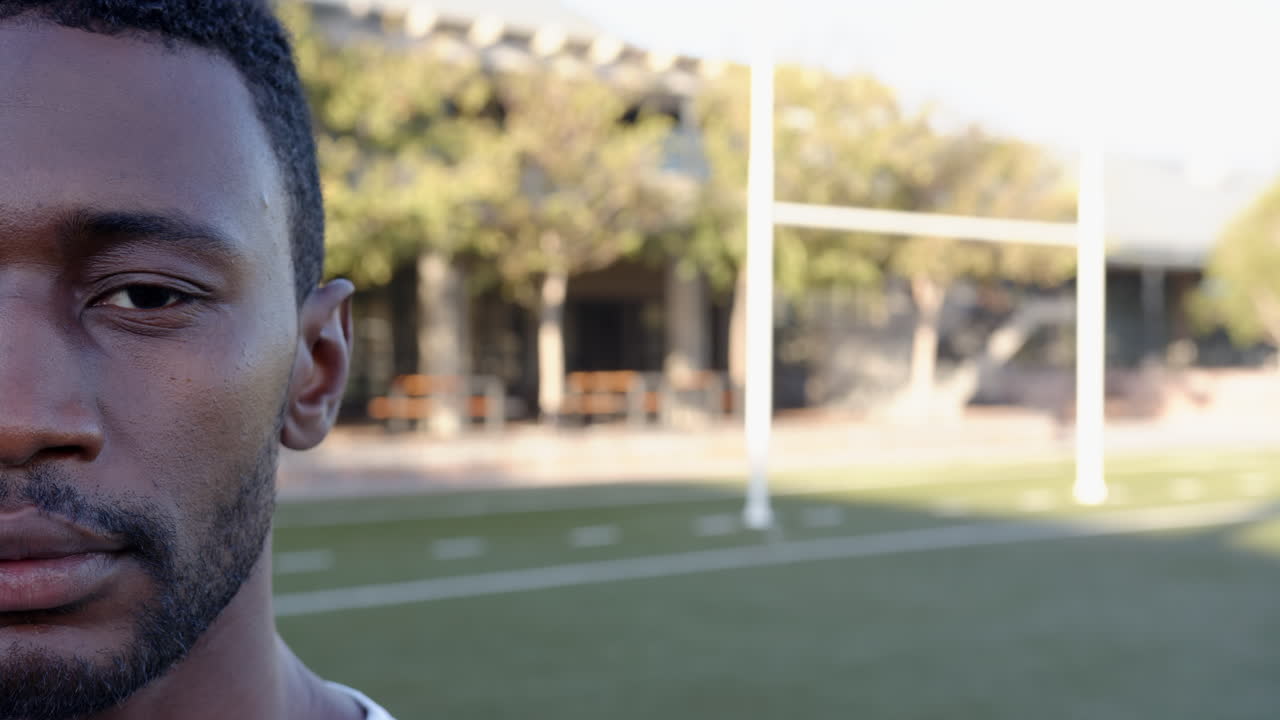 Uomo afroamericano in piedi su un campo da calcio, concentrato sull'allenamento di fitness e sportivo, con spazio per il testo.