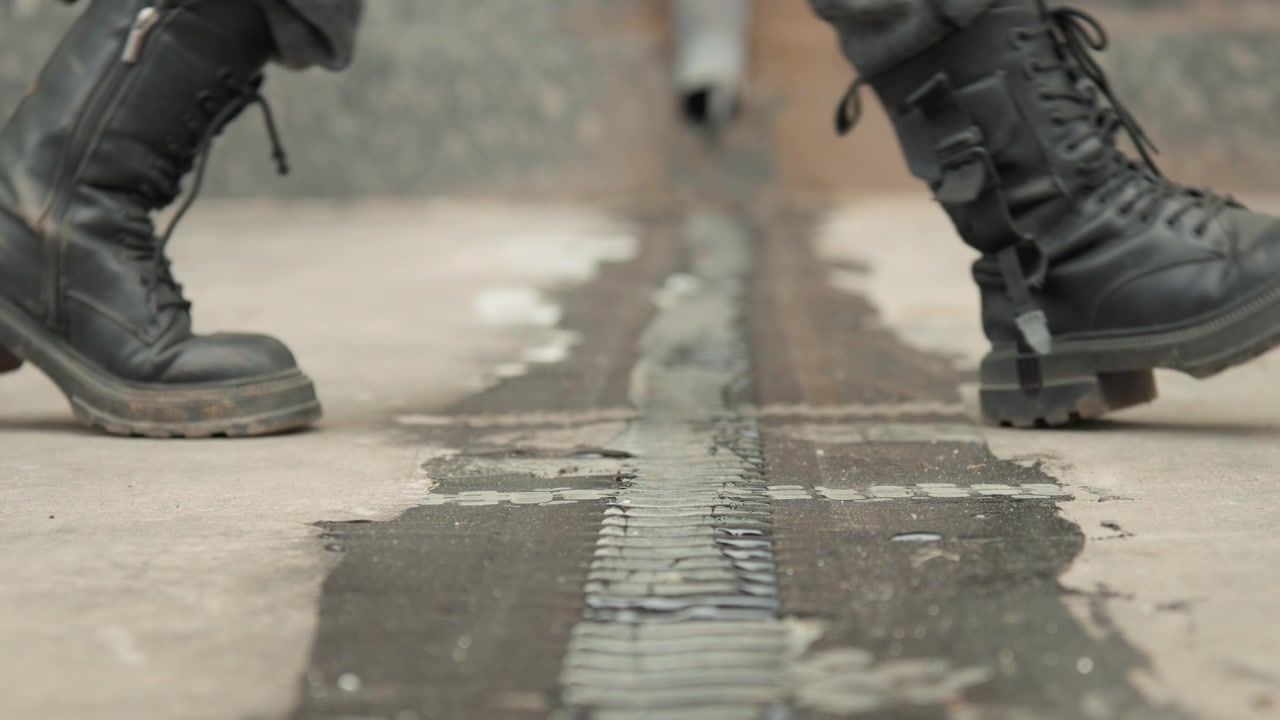 Urban boot stride. Closeup of rugged footwear on city rooftop. Detailed shot of walking boots across urban rooftop surface. Capturing heavy steps and textured detail of footwear on building rooftop