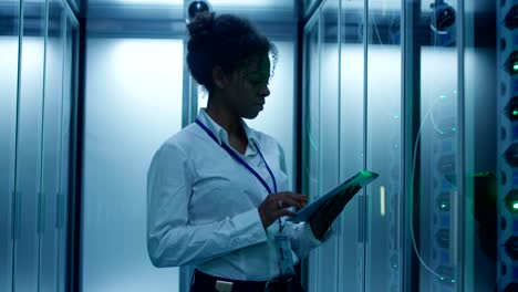 black woman with tablet working in server room