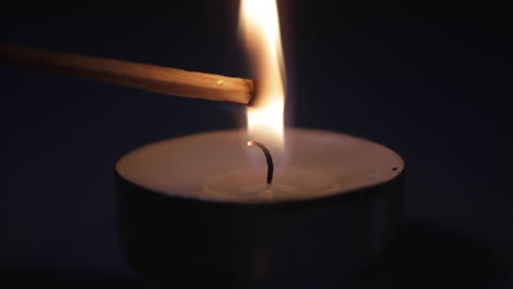 a close up shot of a match being put into the flame of a candle and exploding-lighting