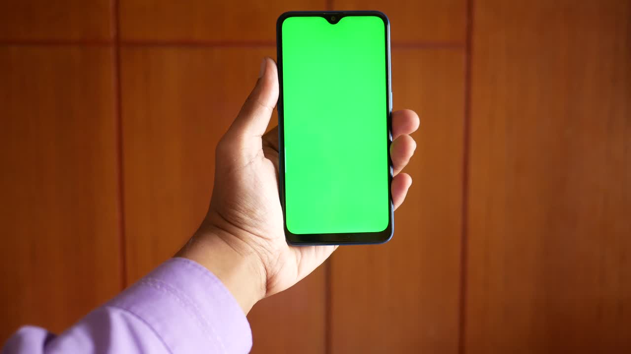 초록색 화면 을 가진 스마트폰 을 들고 있는 손