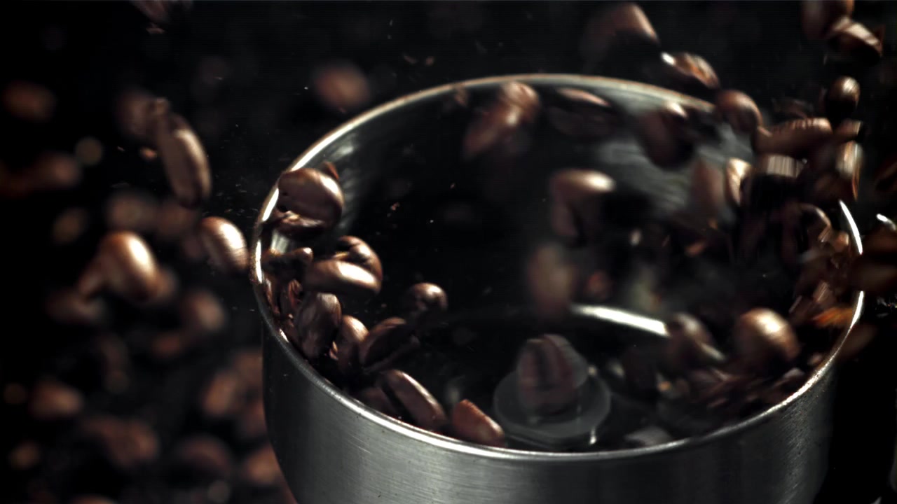 Nærbillede af kaffebønner, der males i en metalkværn i slowmotion