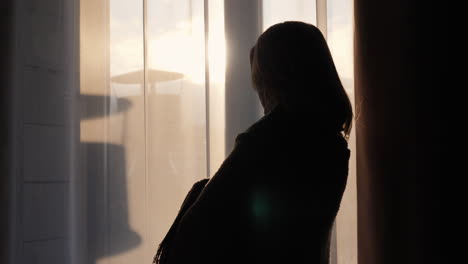 a woman with a warm clothes looks out the window