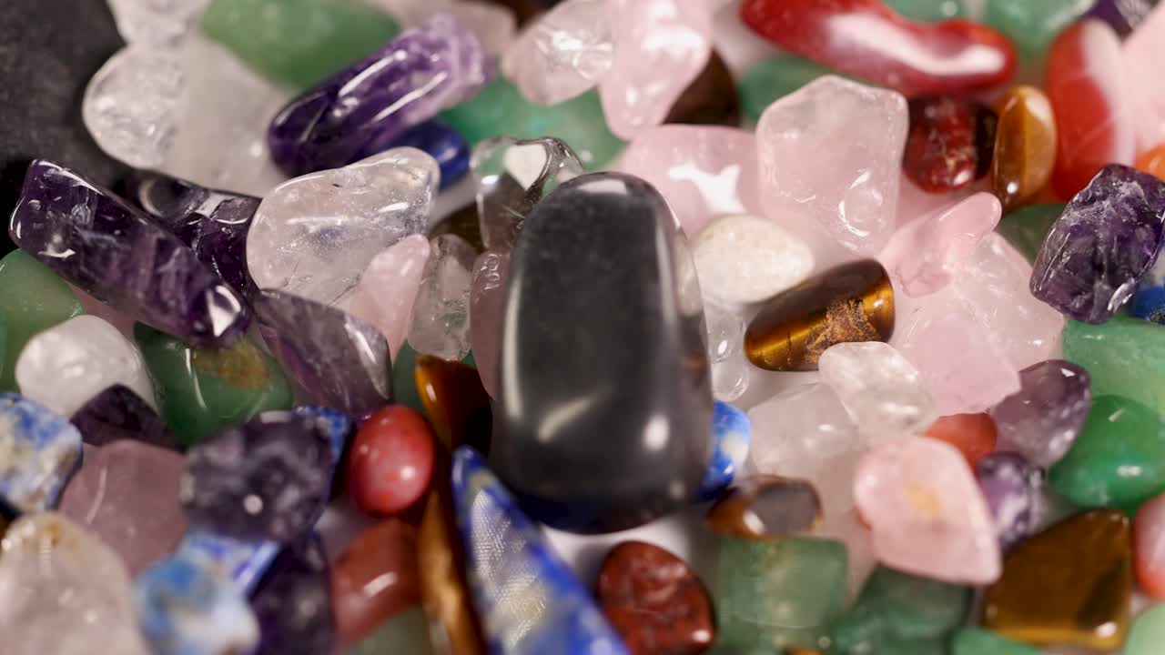 Chakra stones rotate on a vibrant bed of crystals. Bright lighting highlights textures and colors, creating a dynamic visual experience