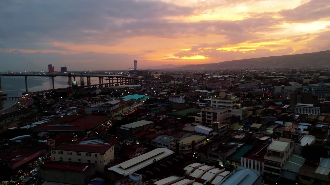 Vista aerea cinematografica del tramonto dorato sullo skyline urbano vivace e sulle acque costiere di Cebu City nelle Filippine.