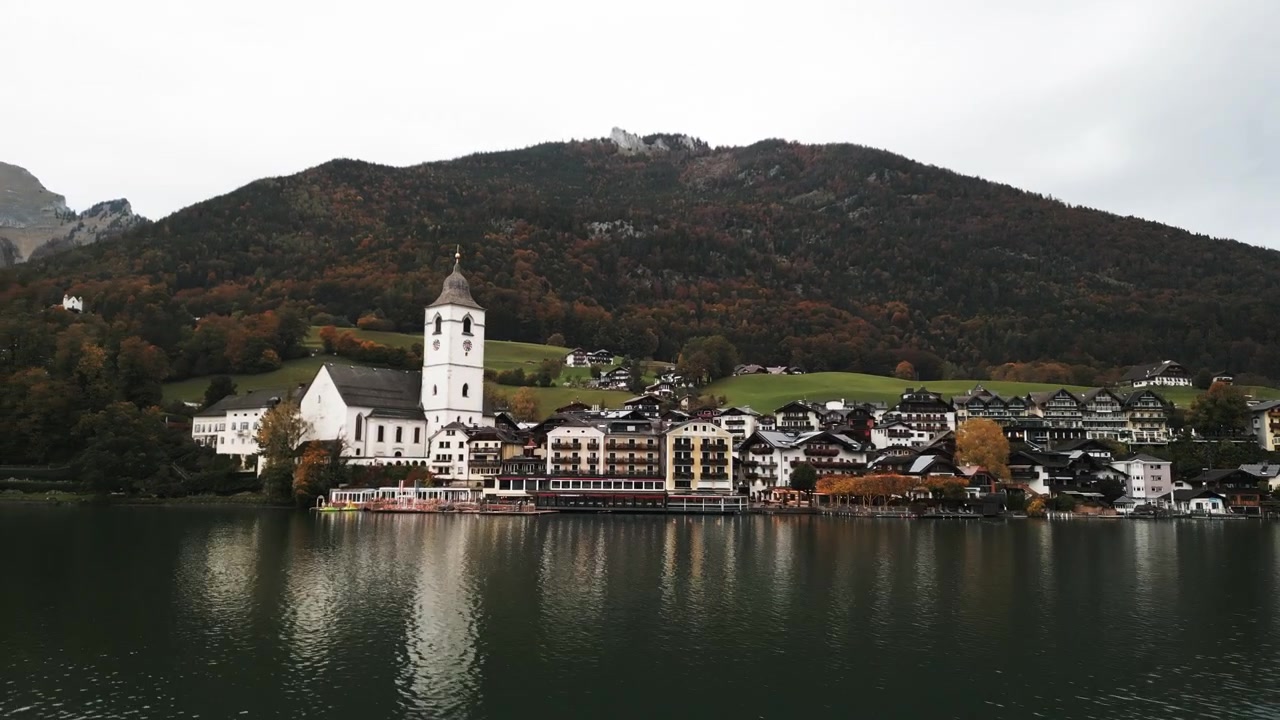 Bewegte Drohnen-Luftaufnahme von Wolfgang am Wolfgangsee an einem bewölkten und nebligen Tag, nah am See.