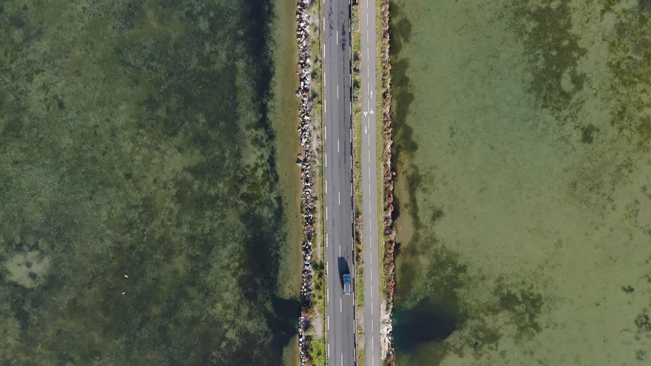 Aerial shot overhead of a van driving over a lake bridge in France