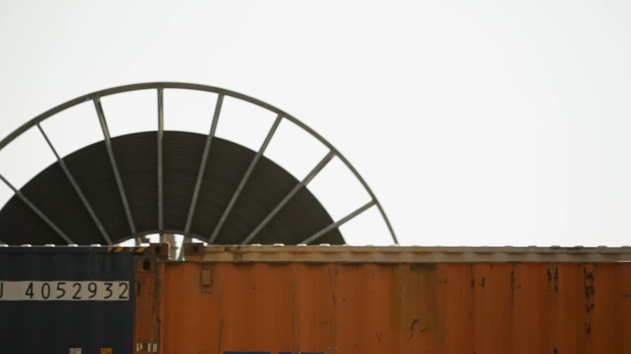Rusty cargo containers with a circular structure in the blurry background, industrial feel