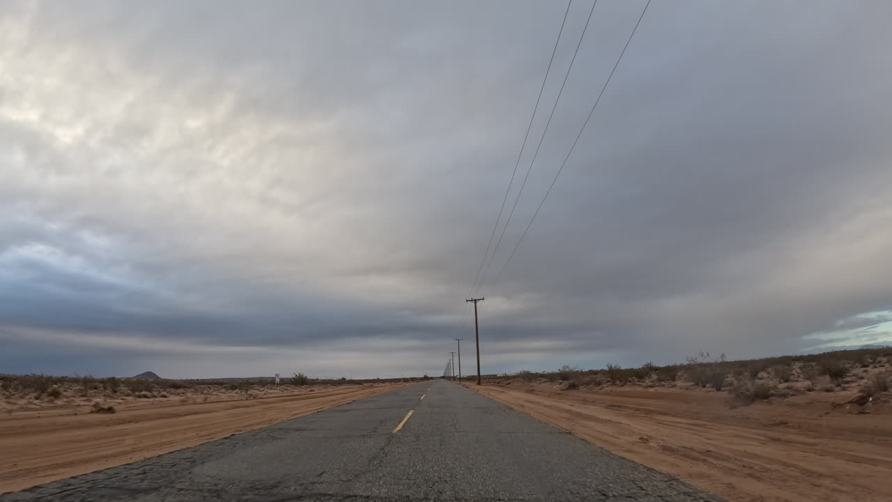 흐린 날 모하비 사막에서 빈 도로를 운전하다
