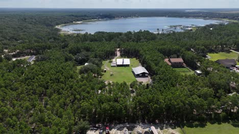 dynamic backward drone movement from a private rural farmland with barn and surrounding green forest trees, panama city beach, florida, usa