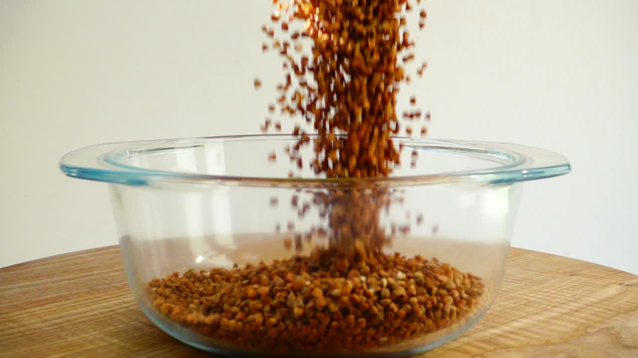 Buckwheat is poured into a glass pan. Slow Motion
