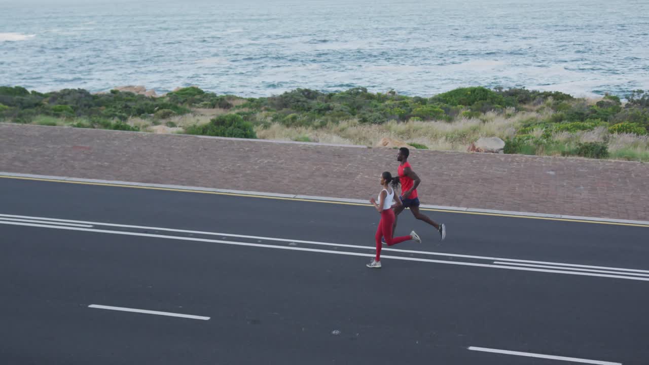 Diverse fit couple exercising running on a mountainside country road