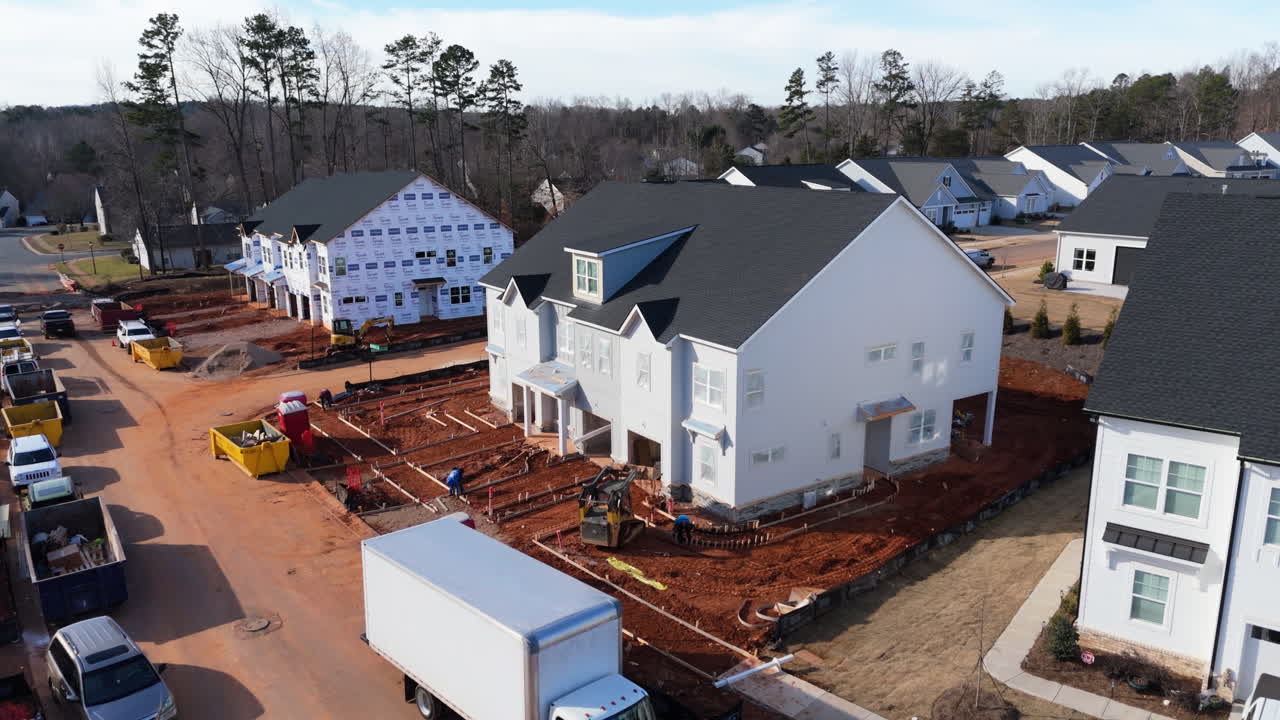 Modern Housing Development Under Construction, With Materials Being Delivered And Heavy Equipment Working. orbiting drone shot