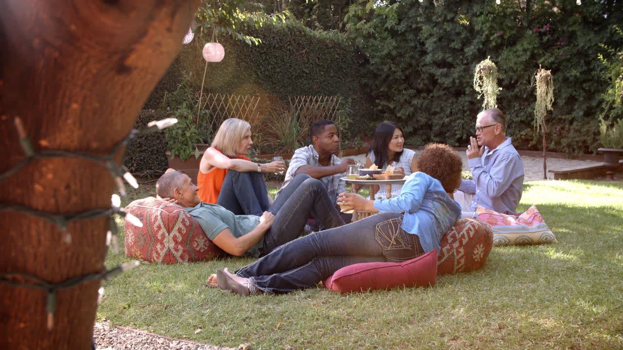 뒷마당 에서 함께 피크닉 을 즐기는 성숙 한 친구 들 의 그룹