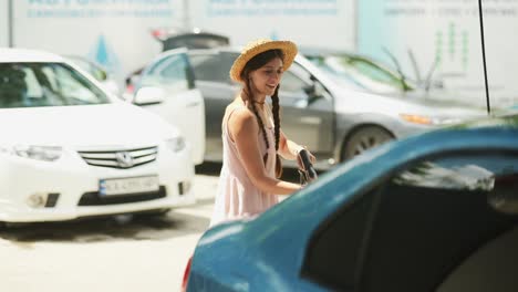 mujer lavando un coche en un lavado de coches de autoservicio