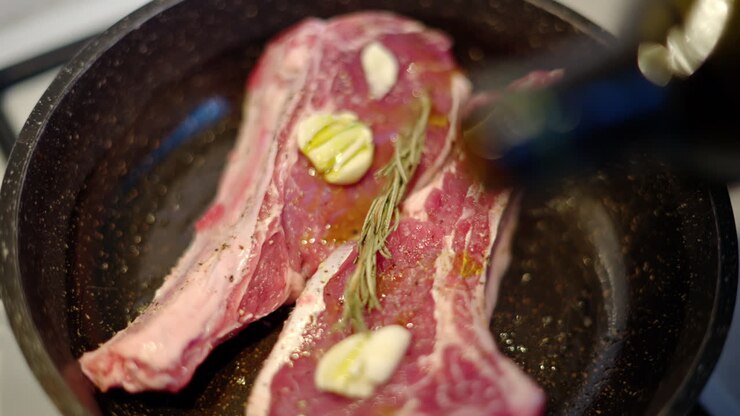 Daging steak iga sapi yang lezat sedang disiapkan dengan rosemary dan bawang putih