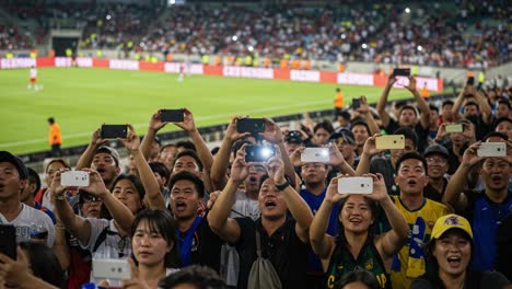 excited fans capturing the thrill of soccer action with their phones in a packed stadium, celebrating the electrifying atmosphere of the game