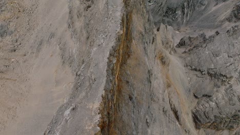 Aerial-tilt-up-shot-showing-rocky-cliff-ravine-of-Monte-Pelmo-Mountain-with-beautiful-valley-view-in-summer