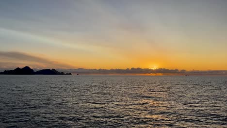 Wide-sunset-view-of-remote-islands-Vestmannaeyjar-in-Iceland-from-boat-on-open-ocean