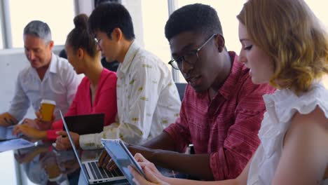 Multi-ethnic business colleagues discussing over digital tablet and laptop in modern office 4k