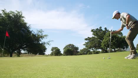 Caucasian-male-golfer-kneeling-on-a-golf-course-on-a-sunny-day