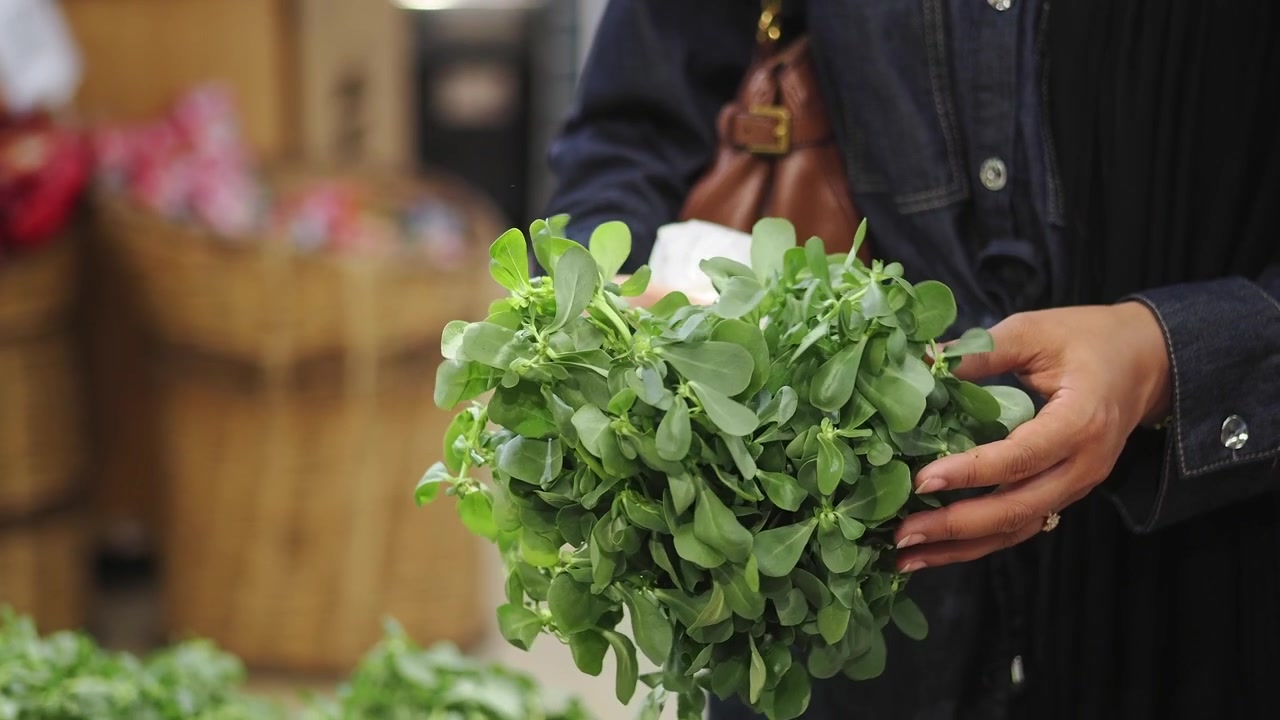Persona che tiene un mazzetto fresco di portulaca al supermercato