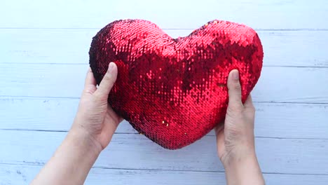 almohada de corazón de lentejas rojas sostenida en las manos