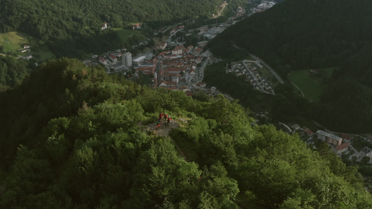 Aerial View of Town Nestled in a Valley with Hikers on a Mountaintop