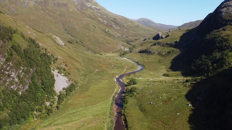 Aerial drone fly above green Scotland Ben Nevis River Valley natural environment landscape in european summer, skyline with pale green mountainous land