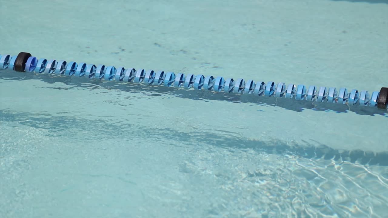 Closeup lane divider in turquoise swimming pool, ripples and no people