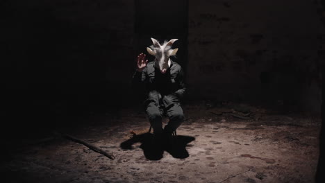 person in goat mask in a dark abandoned room