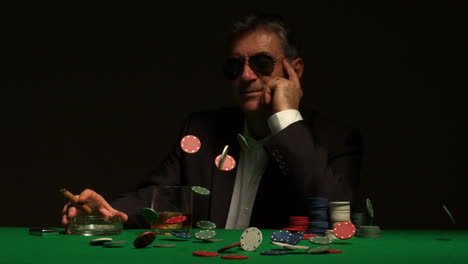 smiling gambler sitting at table with chips falling