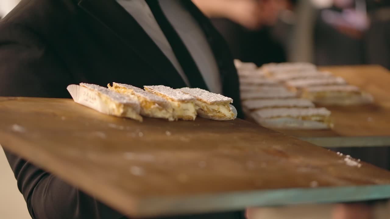 Tjener serverer søde sager på en bakke ved et firmaarrangement