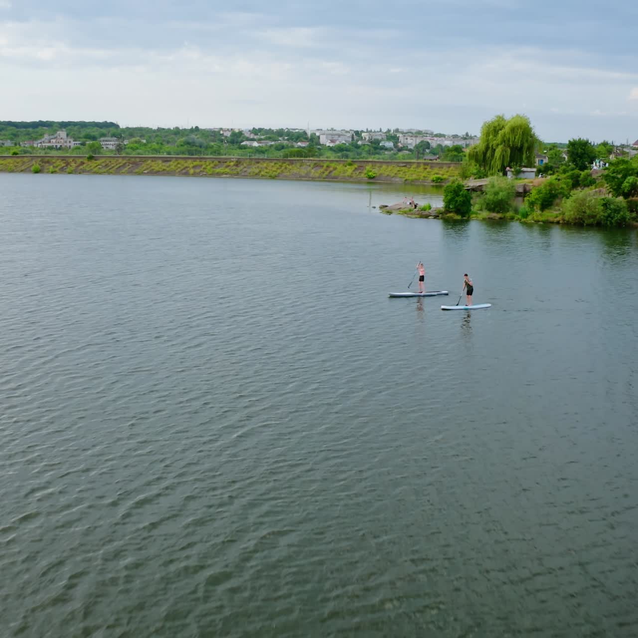 People swimming on boat in summer. Young man and woman with kayakers on water in the river. Travel on stand up paddleboarding in lake. Aerial view